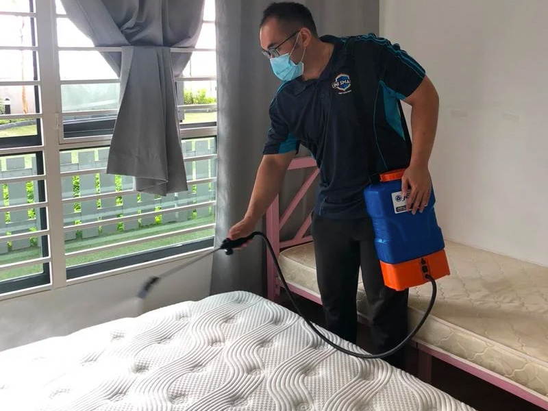 a pest control specialist cleaning a bed infested with bed bugs (pepijat)